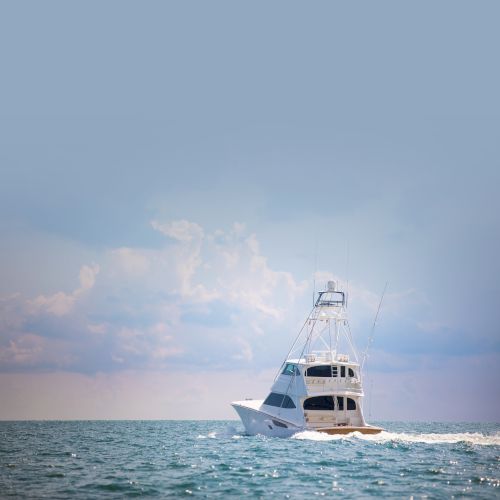 A small lighthouse or beacon on a rocky shoreline with a calm sea and a cloudy sky at sunset.
