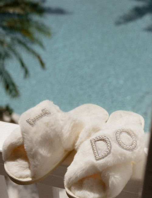 Soft white socks draped over a railing with the letters &ldquo;DO&rdquo; stitched on them, sunny outdoor scene in the background.