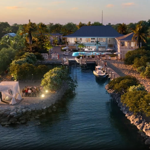 A riverside resort at sunset with a blue-roof lodge, pool, palm trees, and a small dock/boat along the water.